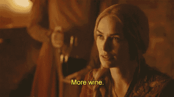 Cersei from "Game of Thrones" holding her glass and asking for more wine.