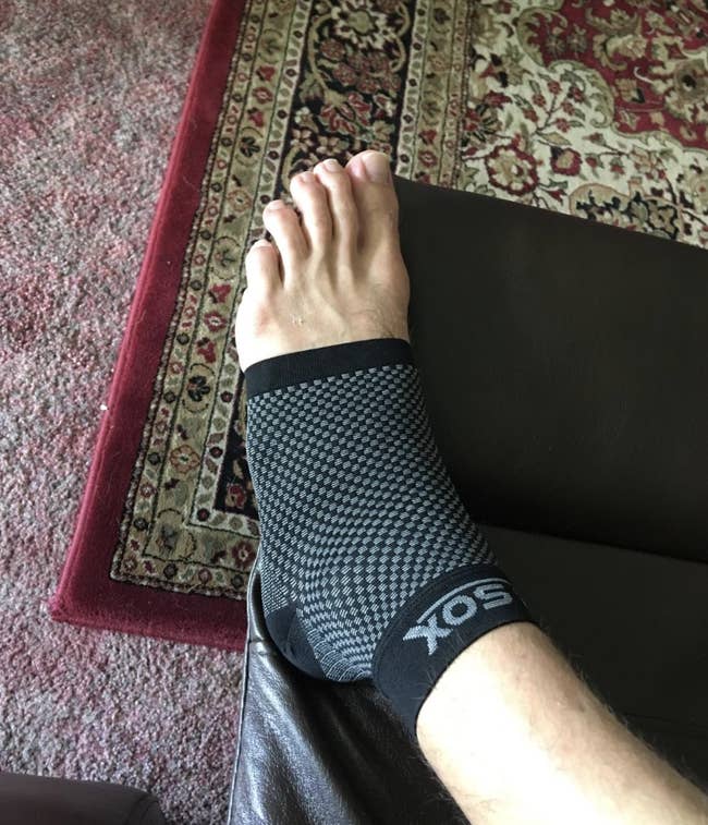 Reviewer in a black compression sock that covers from the bottom of the toes to the top of the ankle 