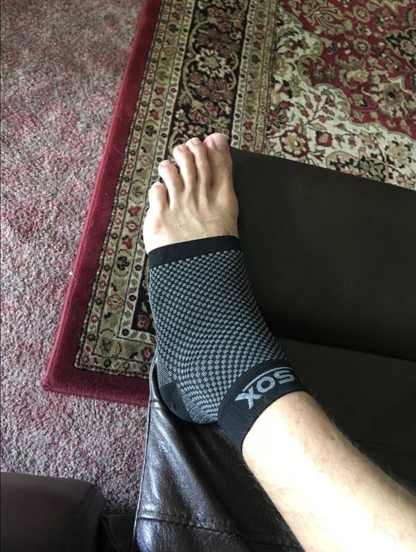 Reviewer in a black compression sock that covers from the bottom of the toes to the top of the ankle 