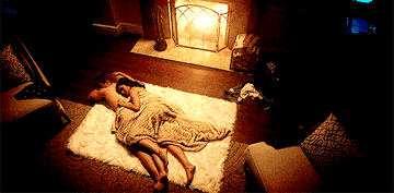 Veronica and Archie sleeping together on a rug in front of a fire