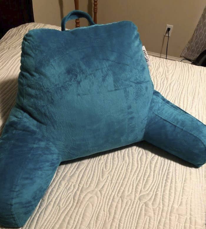 blue velvet pillow with an arm on each side 