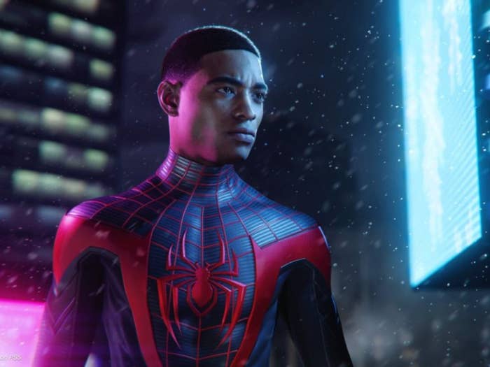 A young man in a black Spider-Man suit stares intently. 