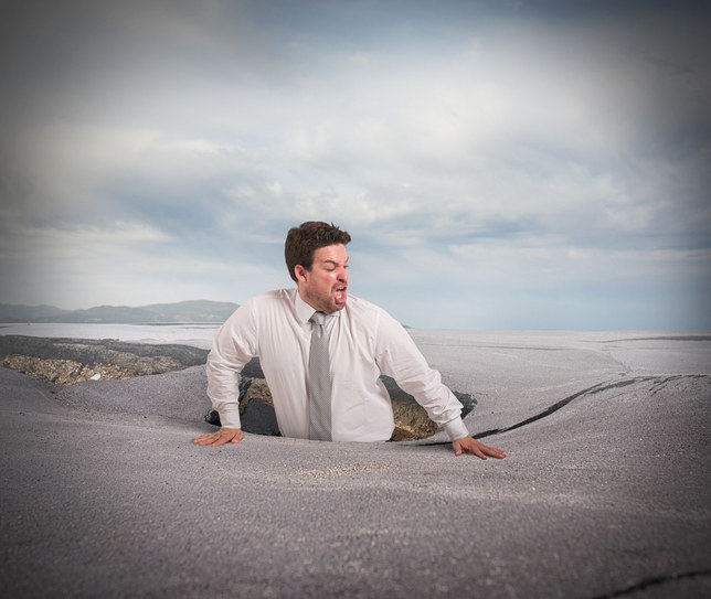 man in suit getting swallowed by quicksand