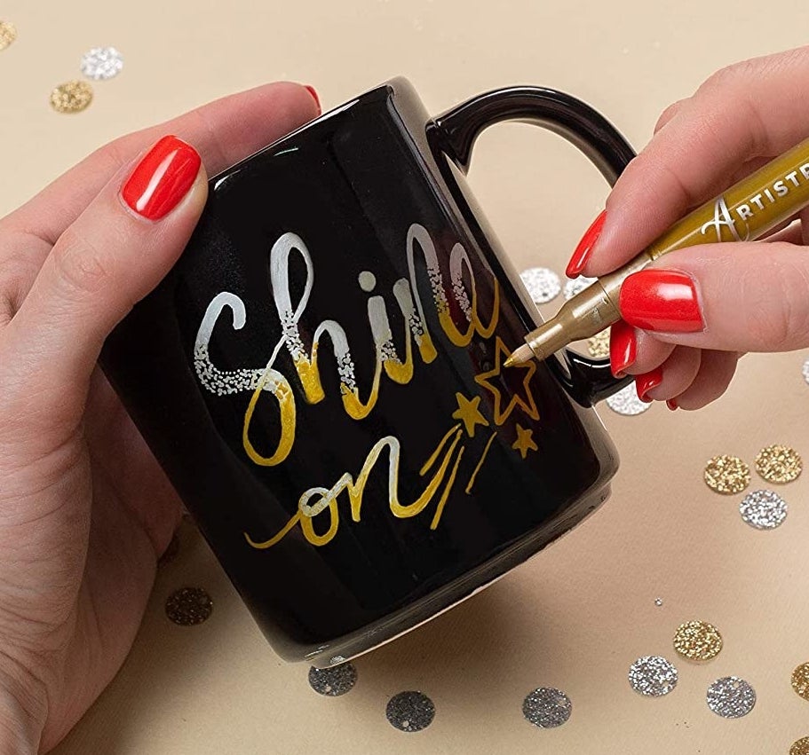 A person writes on a mug using the metallic marker