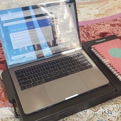 BuzzFeed writer Marquaysa Battle's laptop tray laying flat with her laptop sitting on it and a notebook