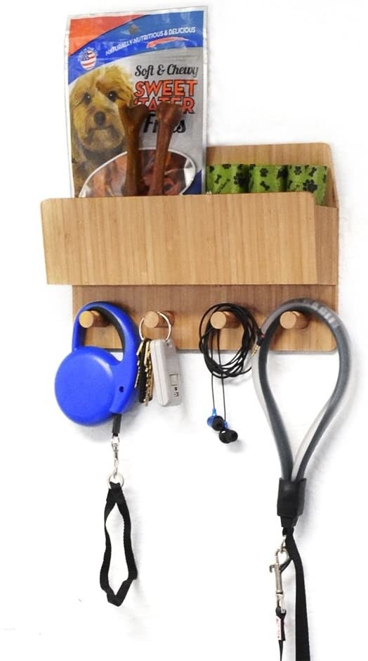 The product is mounted to a wall, holding leashes, keys, and headphones