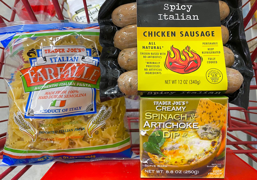 Farfalle, spicy chicken sausage, and creamy spinach and artichoke dip in a shopping cart.