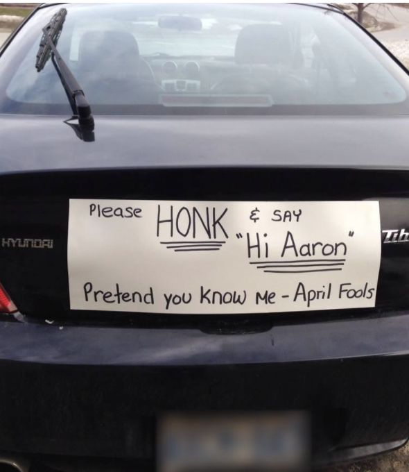 On the back of a car is a sign reading: Honk and say &quot;Hi Aaron&quot; while pretending you know me for April Fools
