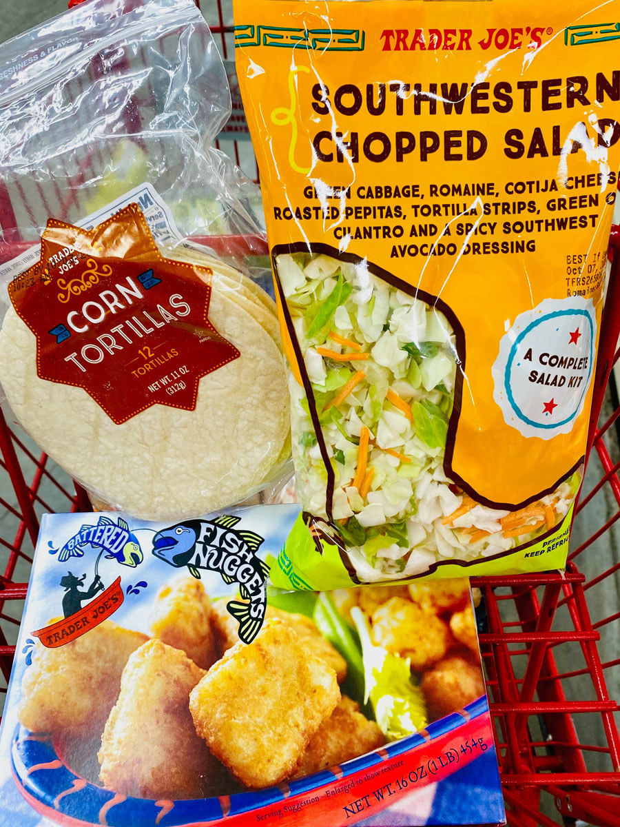 Frozen fish nuggets, southwestern chopped salad kit, and corn tortillas in a shopping cart.