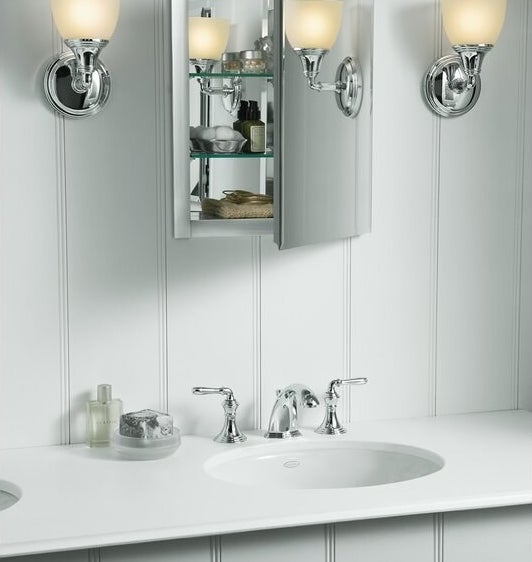 a mirrored medicine cabinet with adjustable glass shelves that are holding bathroom essentials. The medicine cabinet is hung above a bathroom sink