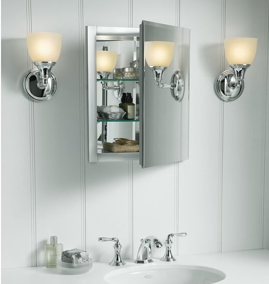 a mirrored medicine cabinet with adjustable glass shelves that are holding bathroom essentials. The medicine cabinet is hung above a bathroom sink