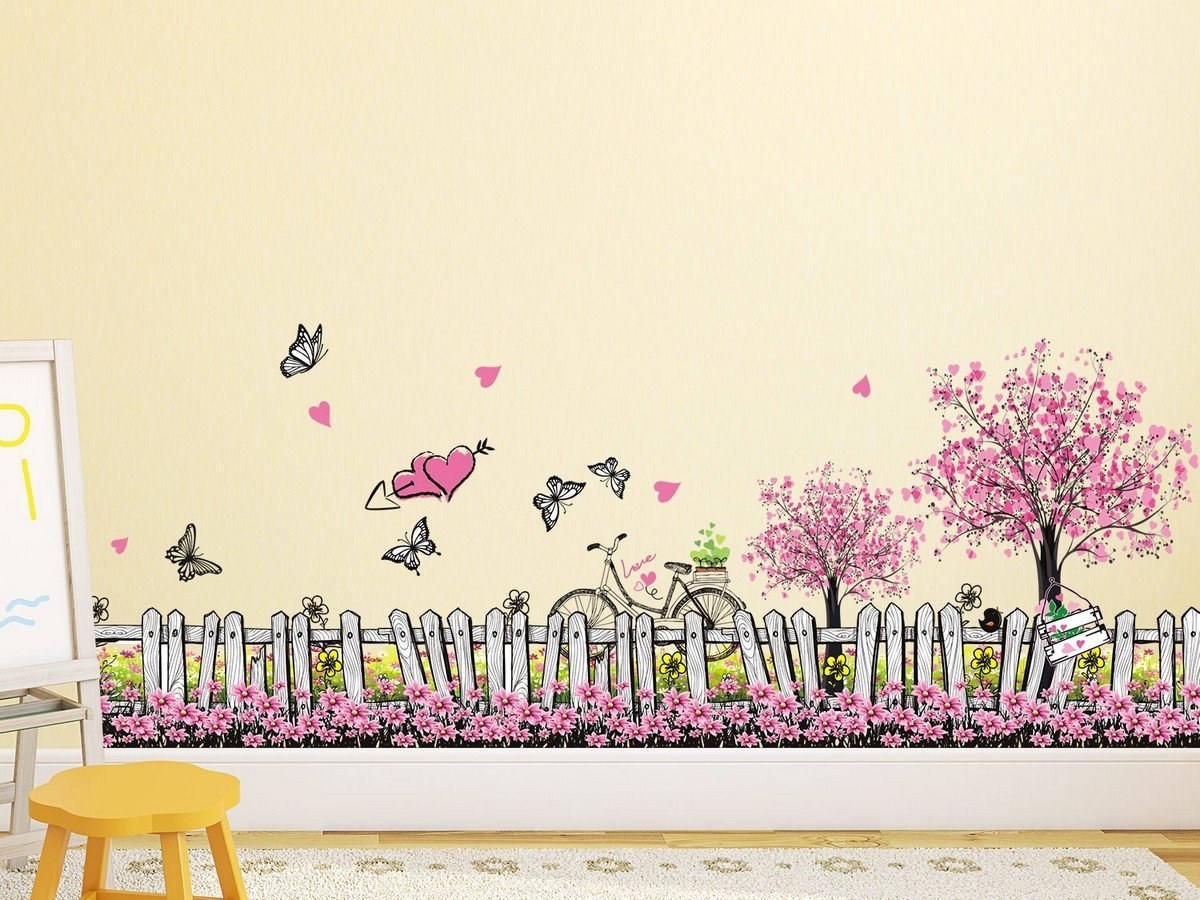 A wall decal with a fenced in park full of cherry blossom trees