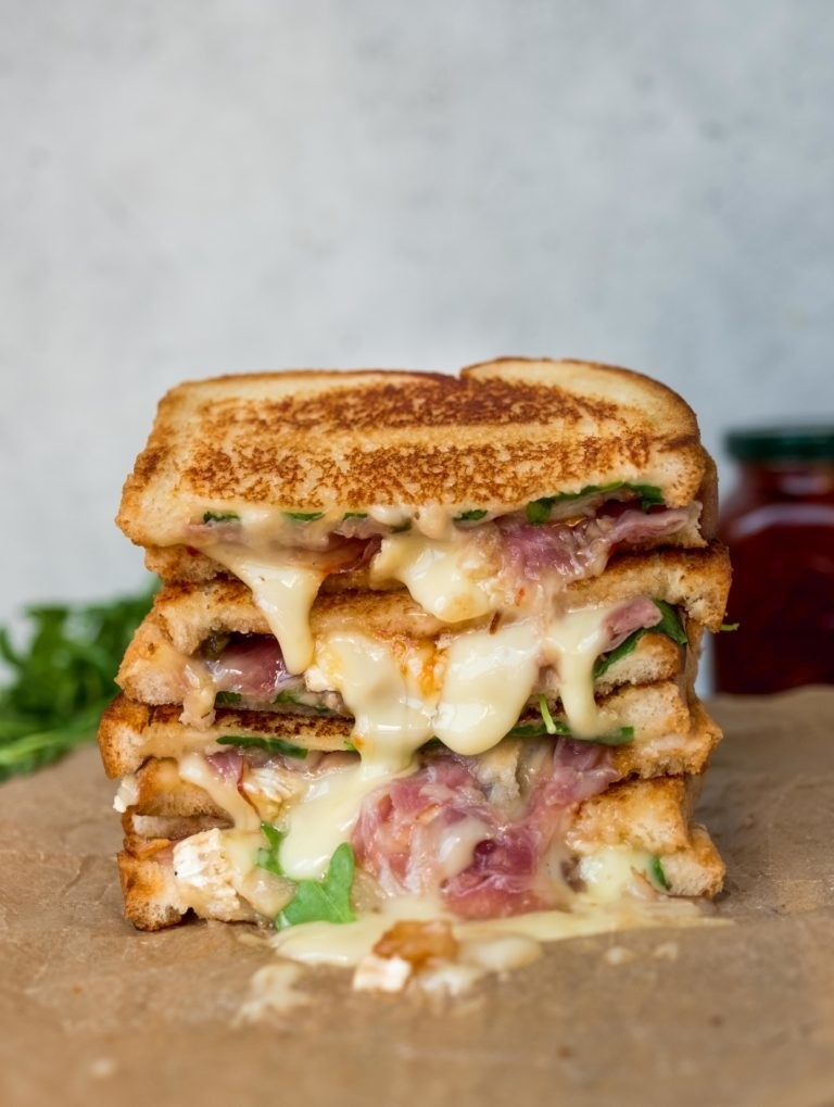 Three halves of a brie and pear grilled cheese with lots of melted cheese.