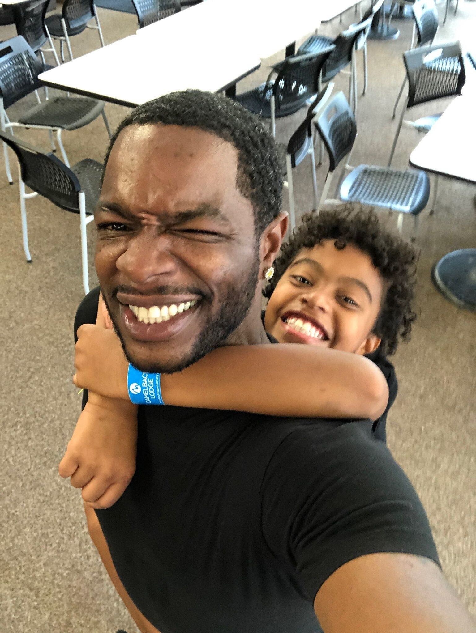 Kyle holds onto his dad&#x27;s back as they pose for a selfie