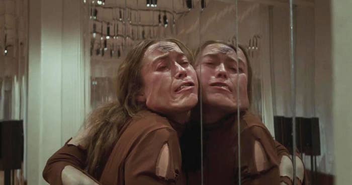 A disfigured dancer with her face pressed against a ballet mirror
