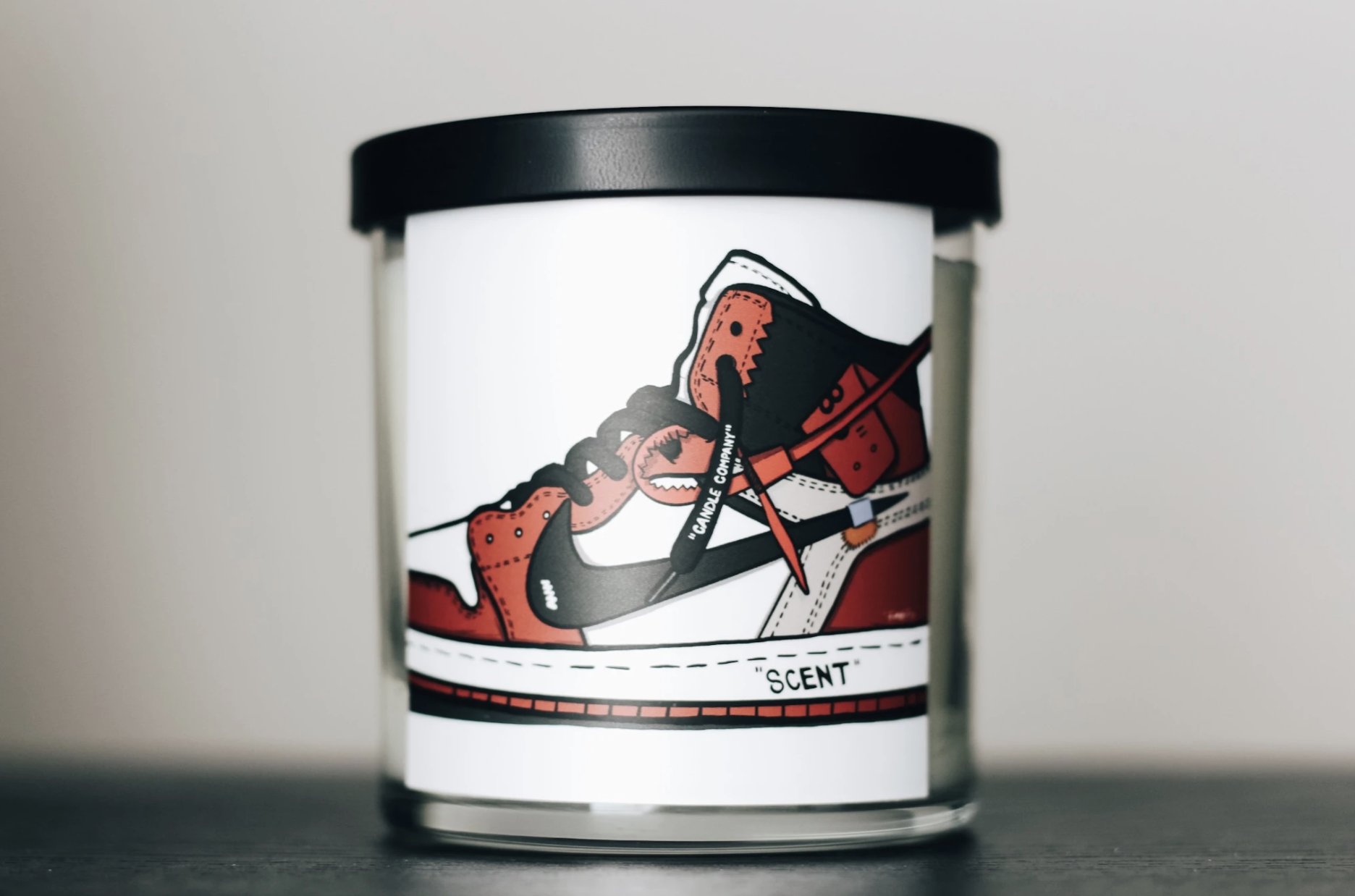 The candle has a picture of a red, black and white Air Jordan 1 sneaker on it 