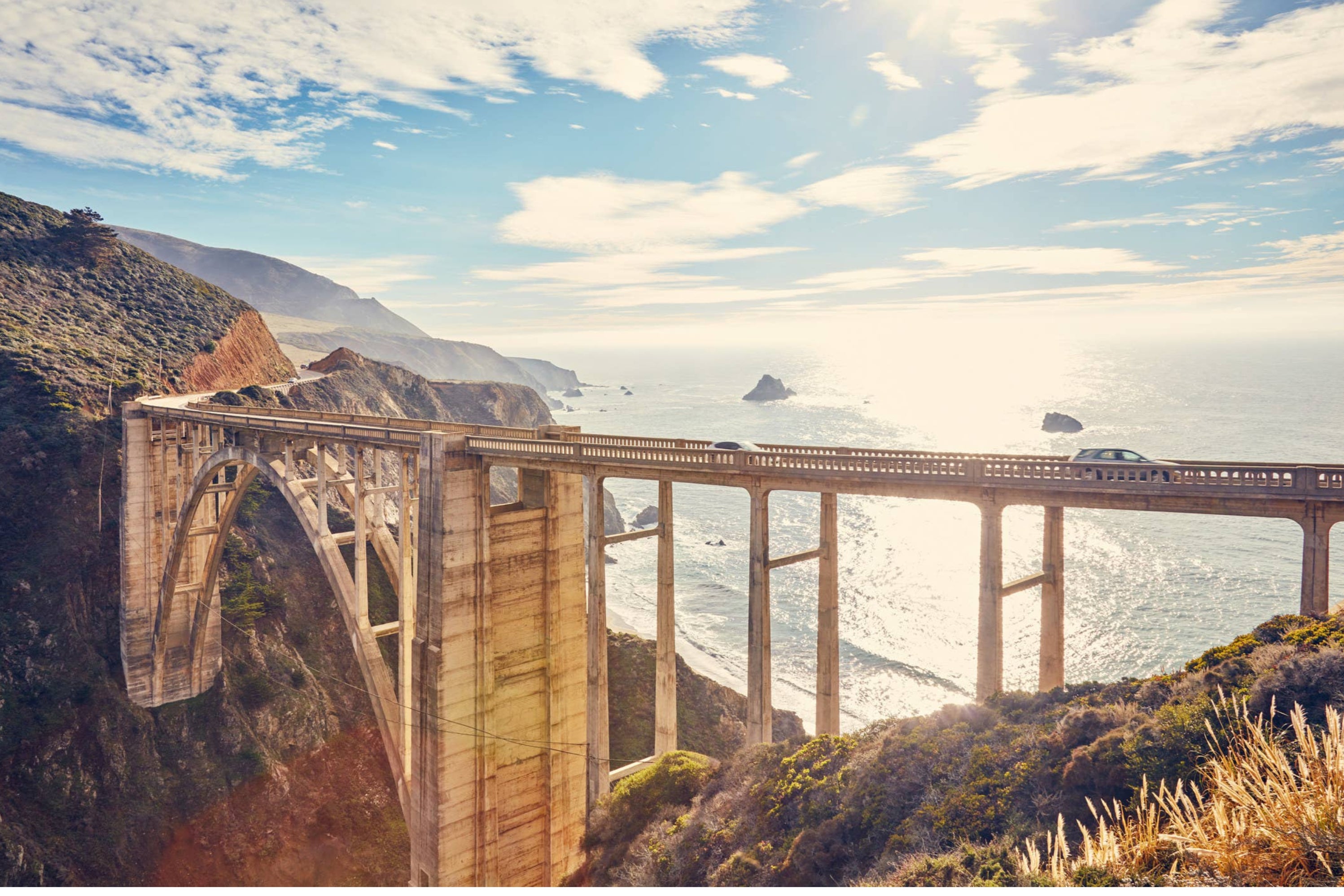 Bixby Creek Bridge at sunset with rocky cliffs and a view out across the ocean