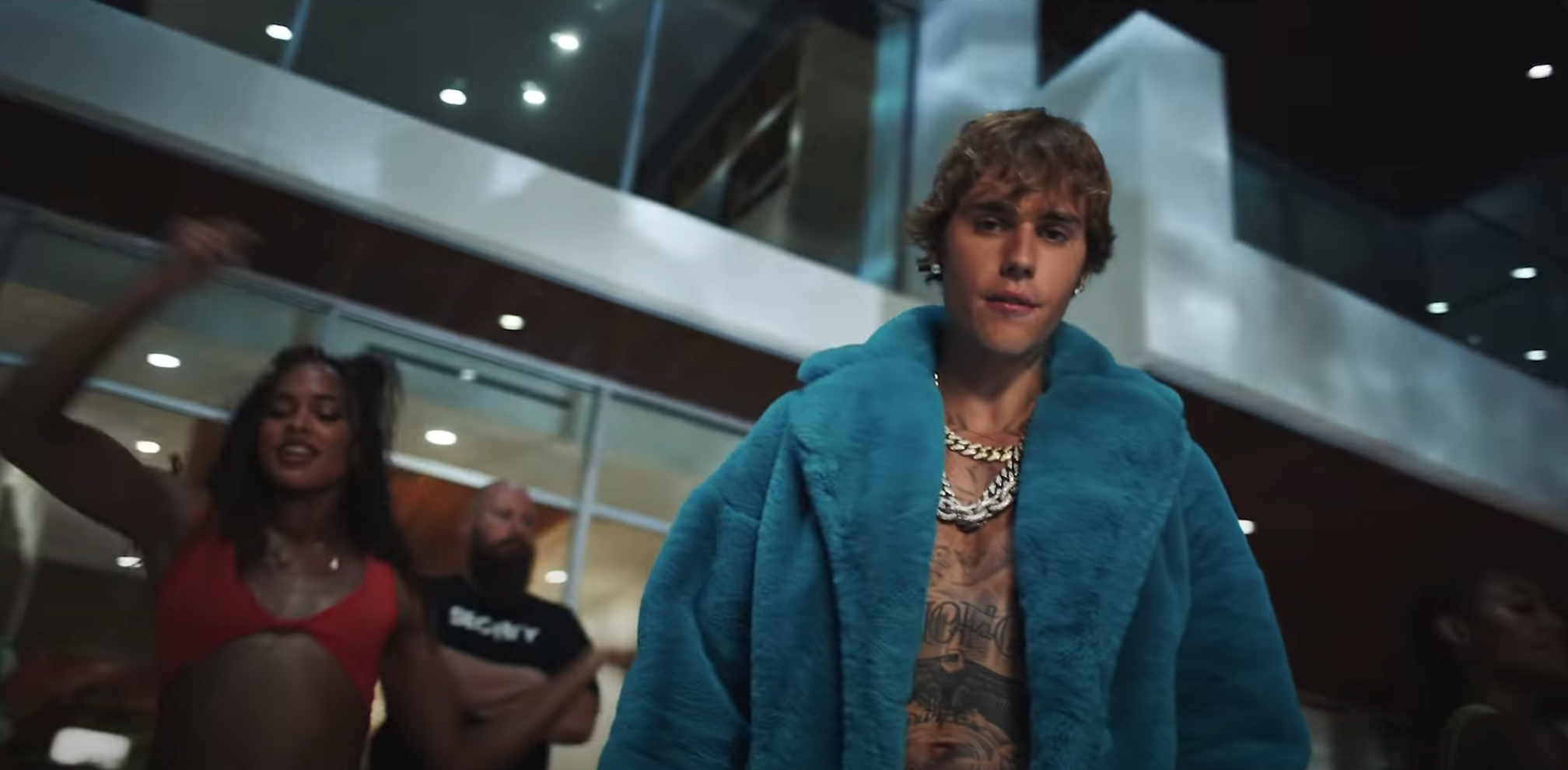 Justin wears an oversized fur coat among other dancers 