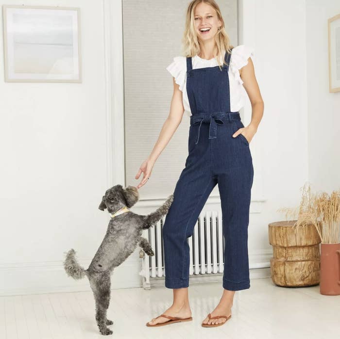 Model wears overalls with white ruffled top