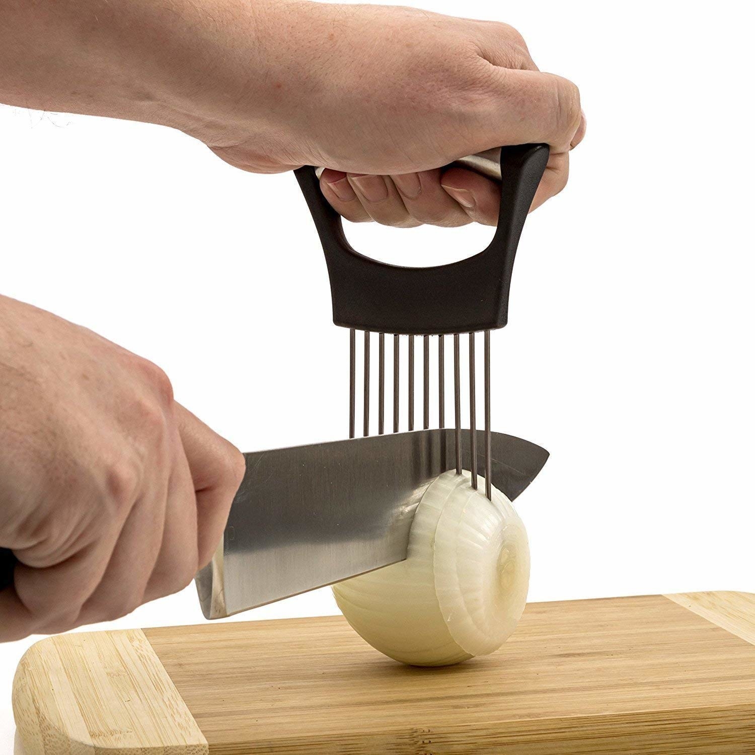 A black vegetable holder being used to cut an onion on a wooden board