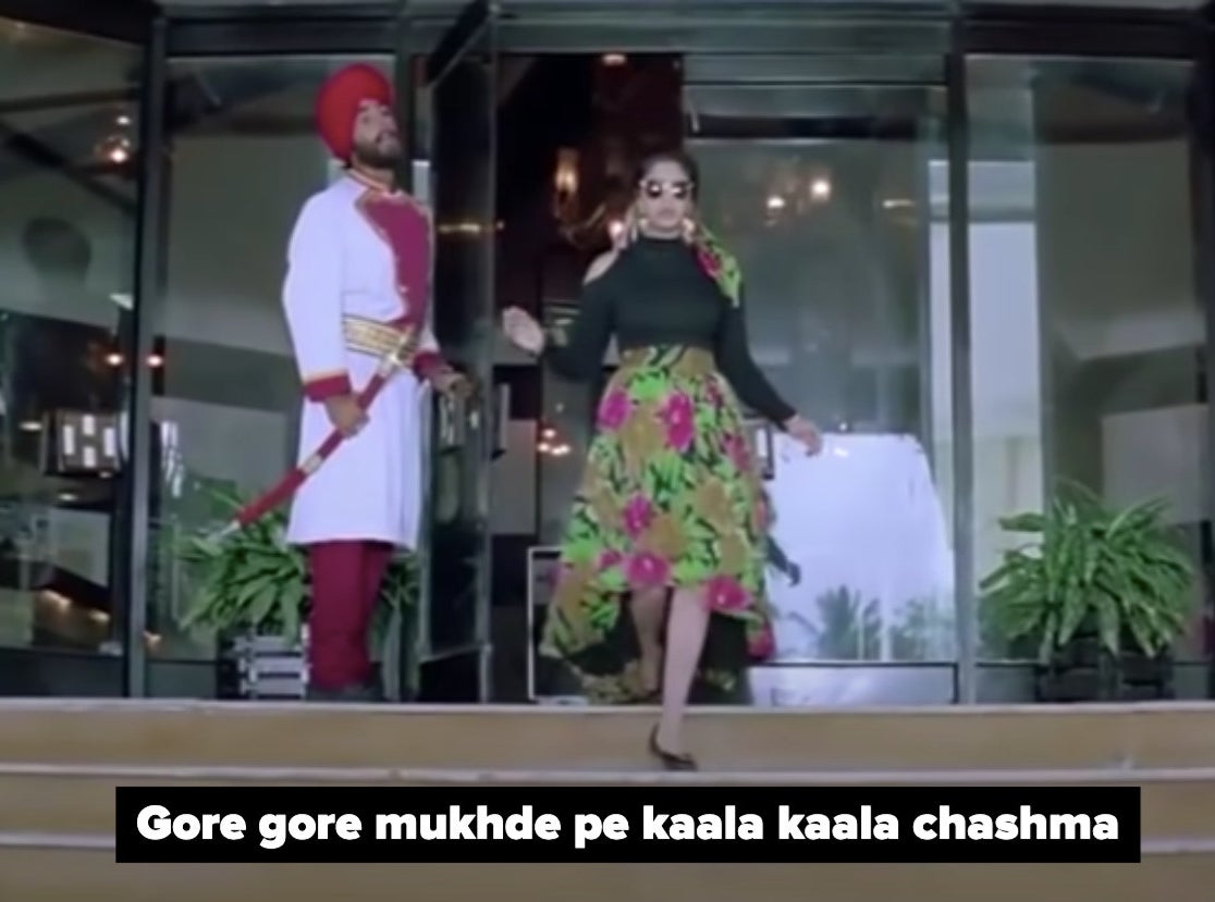 akshay kumar holds a glass door open while nagma walks out and starts descending some stairs