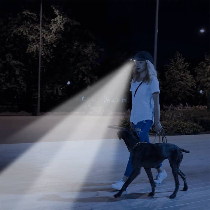 A person walks their dog with a hat that lights their way