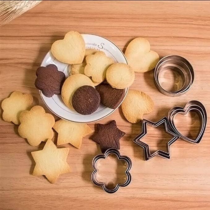 A plate of cookies In various shapes  on a white plate surrounded by the cookie cutters