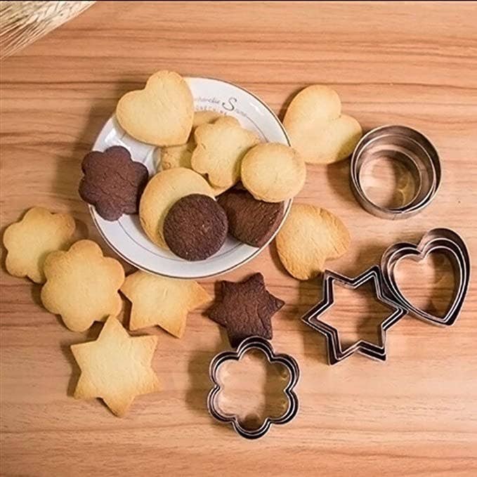A plate of cookies In various shapes on a white plate surrounded by the cookie cutters
