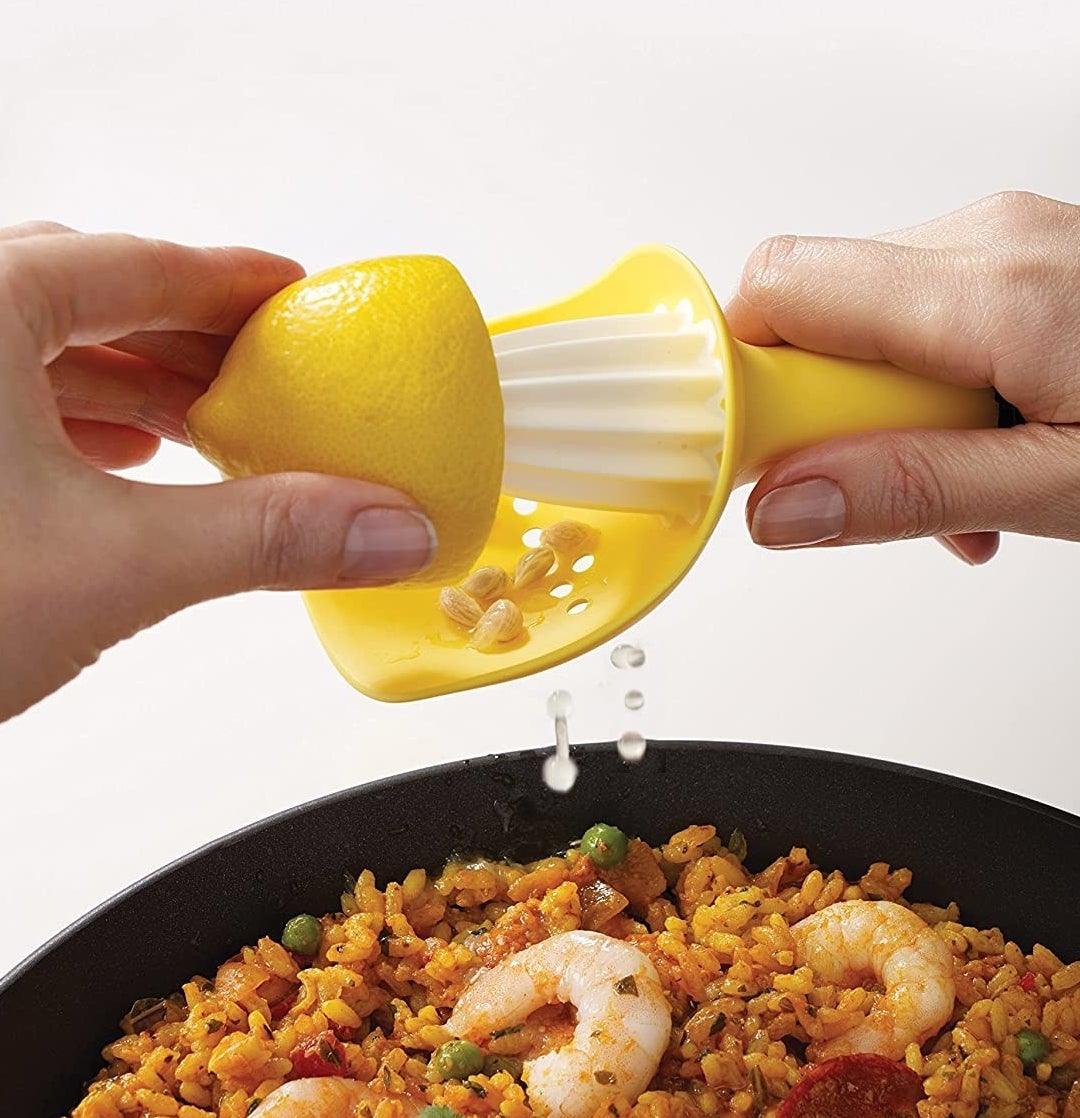 A person using the citrus reamer to juice a lemon over a rice dish