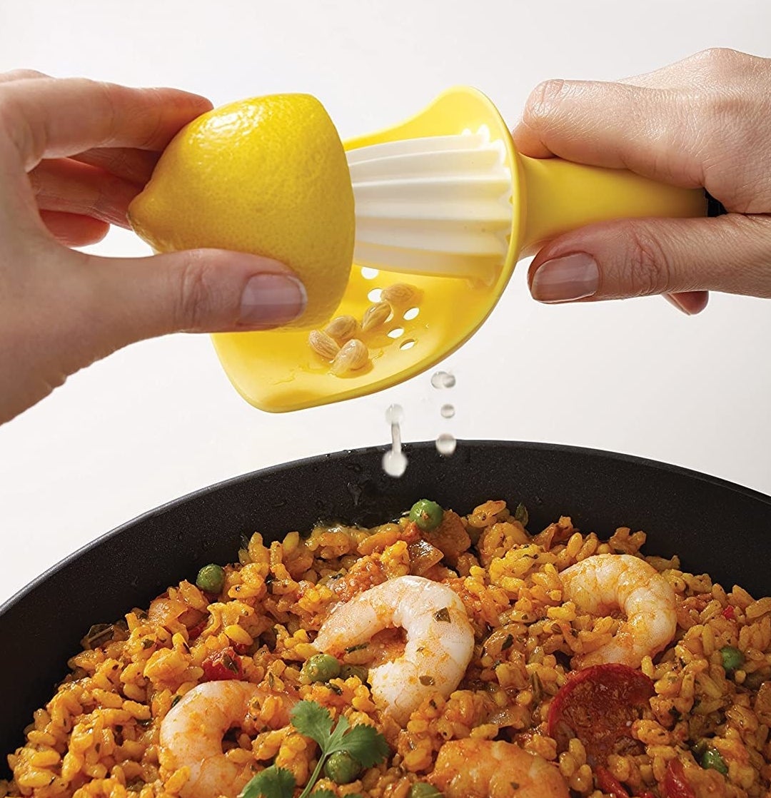 A person using the citrus reamer to juice a lemon over a rice dish