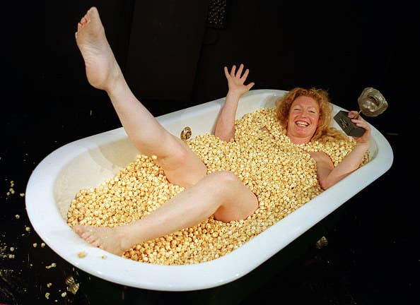 woman in bath filled with popcorn laughing