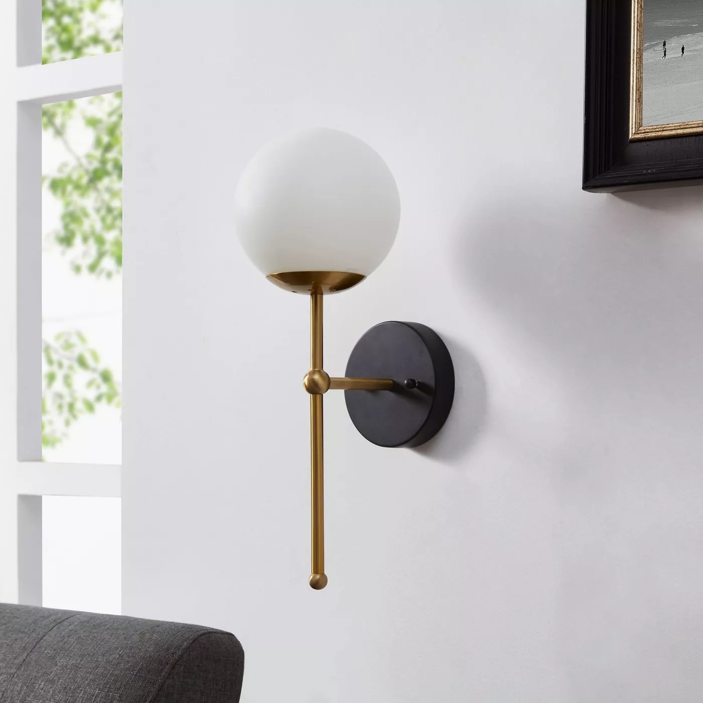 The 16-inch brass wall sconce with a white glass globe