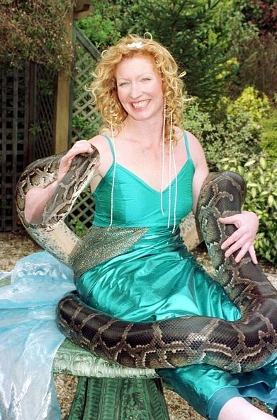 woman dressed as a mermaid in green dress holding large snake