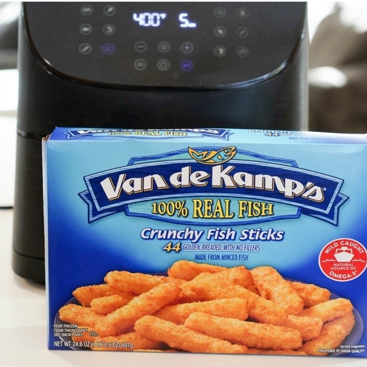 Frozen boxed fish sticks in front of an air fryer.