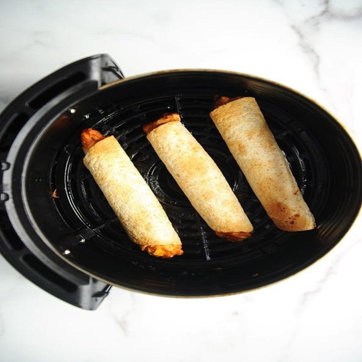 Three chicken taquitos in golden brown tortillas in the air fryer.