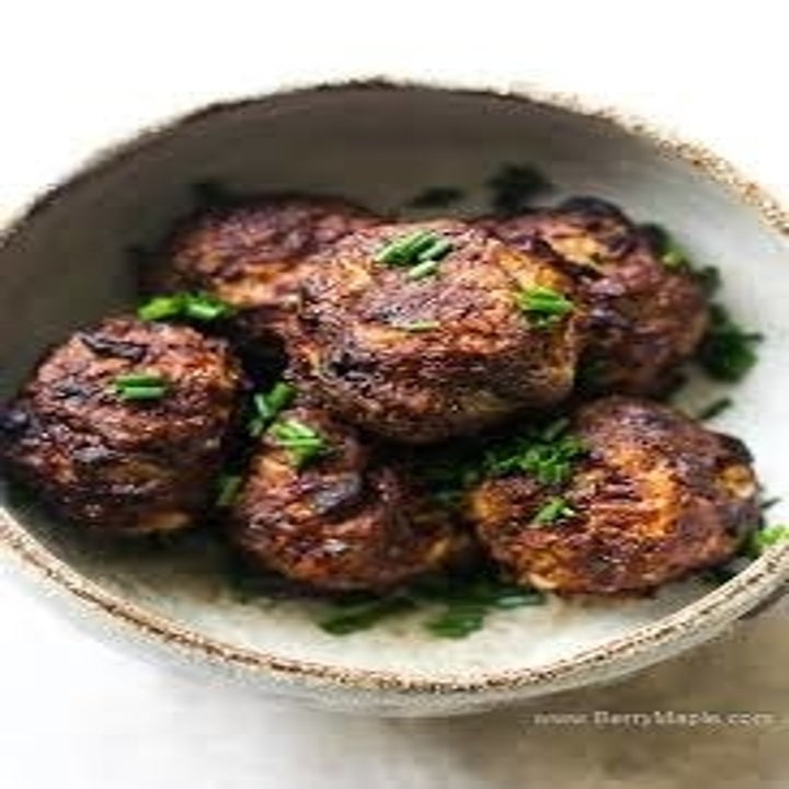 A bowl of homemade meatballs topped with chopped scallions in a bowl.