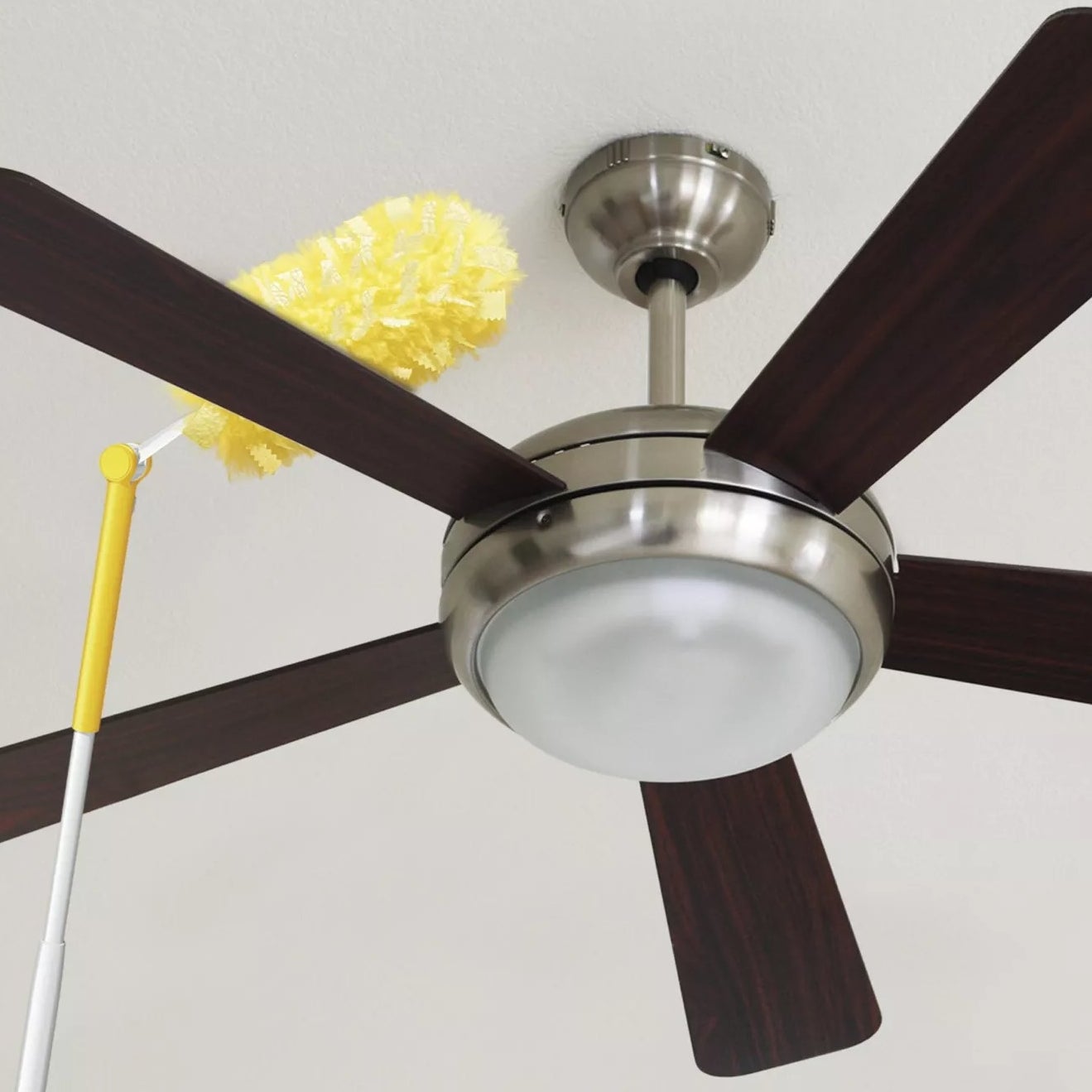A Swiffer Duster angled to clean the top of a ceiling fan blade
