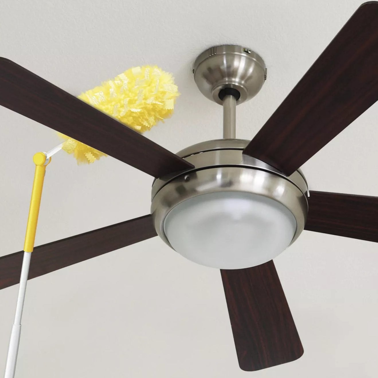 A Swiffer Duster angled to clean the top of a ceiling fan blade