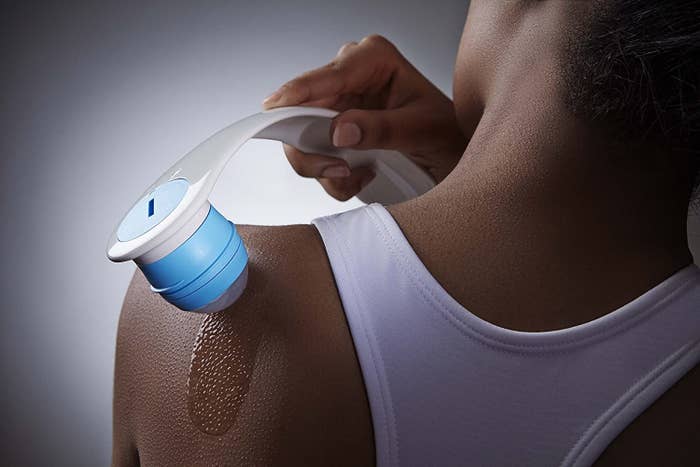 Person using handle to apply lotion to back of shoulder 