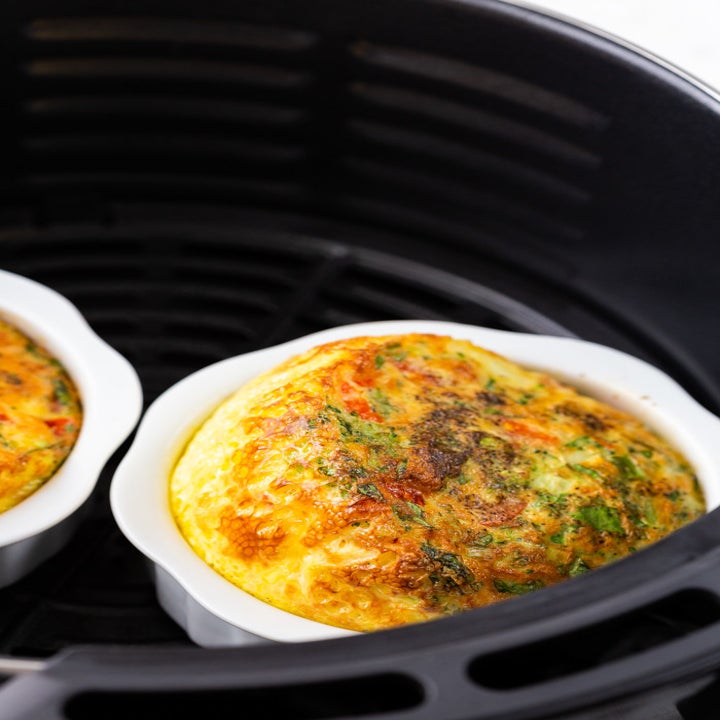 Two baked egg cups in an air fryer.
