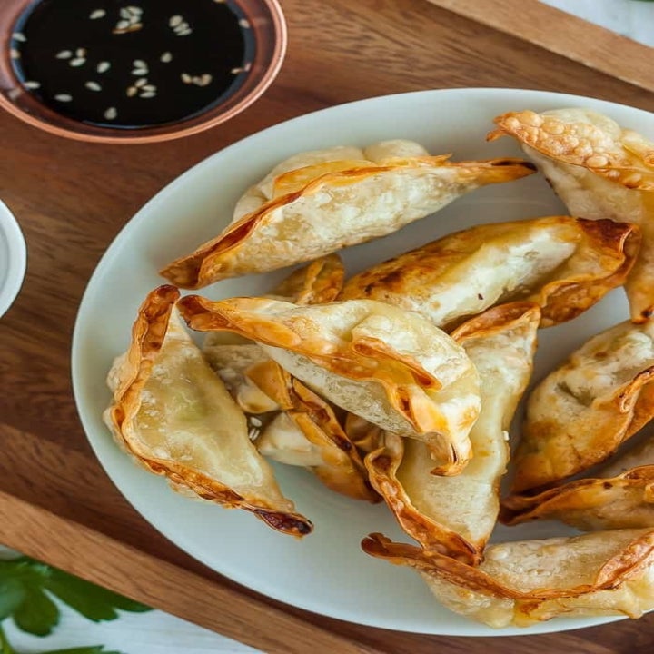 Air fried pot stickers on a plate with a side of Asian dipping sauce.