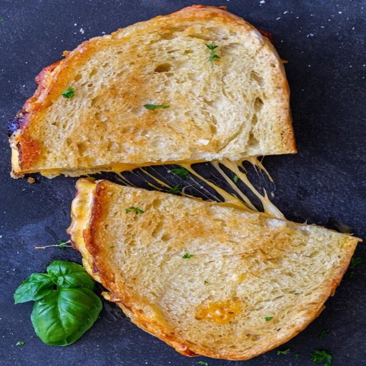A grilled cheese sandwich with golden brown bread cut into half.