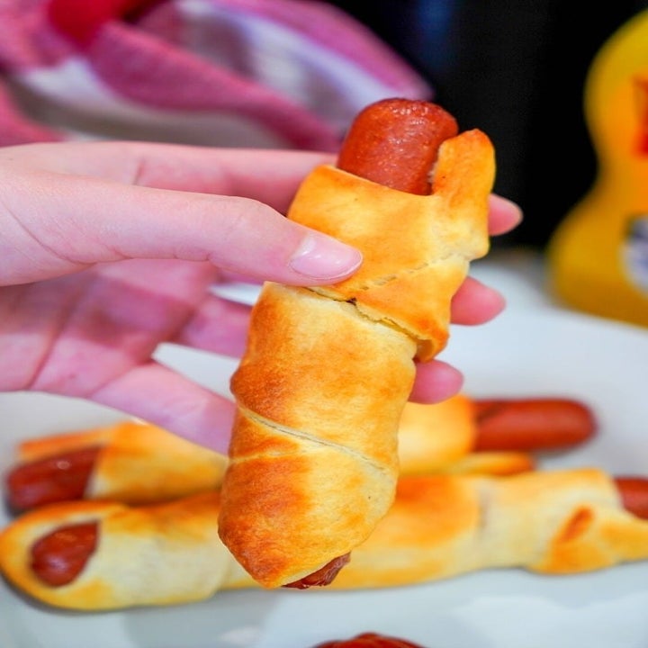 Someone holding a hot dog wrapped in crescent dough.