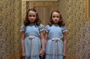The twins from the movie The Shining standing at the end of the hallway
