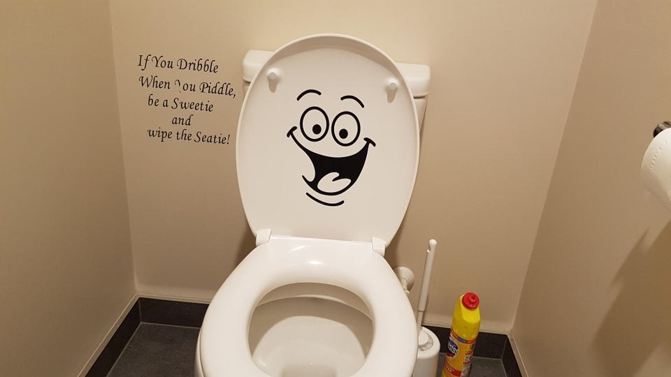 A toilet seat with a big grinning face decal on it