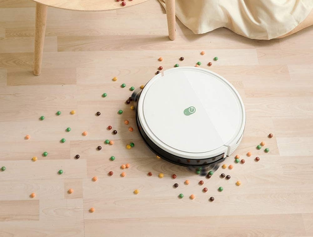 a white circular robot vacuum cleaning up candy