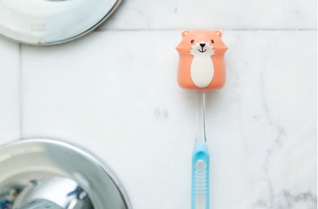 The toothbrush holder holding a toothbrush against a wall