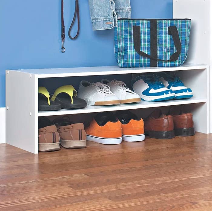 The white shoe rack holding sneakers, sandals, and loafers