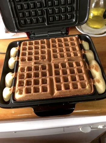 Reviewer image of the waffle maker open, showing how the overflow channel on the sides catch batter