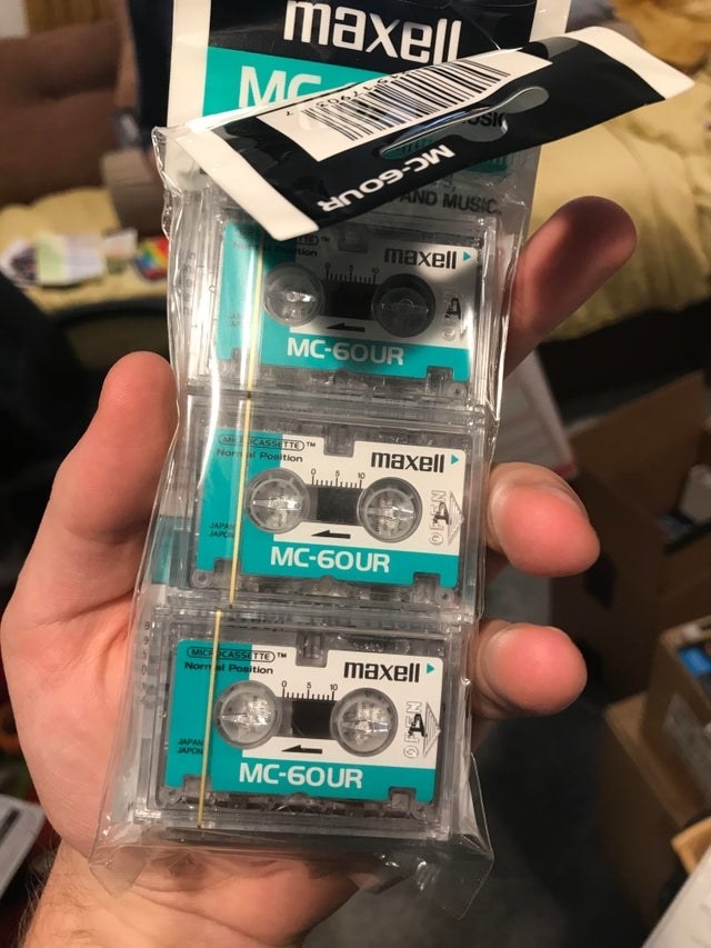 A hand holding a package of Maxell mini-cassettes 